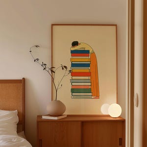 Puede incluir: Una lámina enmarcada con el dibujo lineal de una persona de pelo oscuro con una camiseta amarilla de manga larga y pantalones naranjas, apoyando la cabeza sobre una alta pila vertical de libros coloridos en tonos rojos, azules, amarillos y verdes.