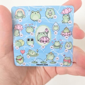 May include: A square blue savings tracker card featuring various illustrations of light green frogs in different poses, including with lotus flowers, rainbows, and drinks. The card includes currency symbols and the text Saves £24 at the bottom.