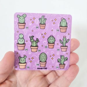 May include: A square purple savings tracker card featuring nine illustrated green cacti in terracotta pots. Each cactus has a smiling face and is surrounded by small yellow star icons. The text "Saves £20" is printed at the bottom centre.