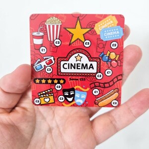 May include: A square red card featuring cinema-themed illustrations including a popcorn bucket, a drink, 3D glasses, a film strip, theatre masks, and a hot dog. The card displays the text CINEMA and Saves £23, with various £1, £2, and £3 icons.