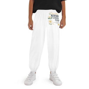 May include: White sweatpants with a drawstring waist and elastic cuffs. The pants feature a floral design and the text "Jesus Loves You" in blue and green. A smiling face is also included in the design.