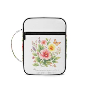 May include: White crossbody bag with a floral watercolour design. The design includes pink, yellow, and purple flowers, green leaves, and a butterfly. The bag has a black zip and the text "His mercies are new every morning."