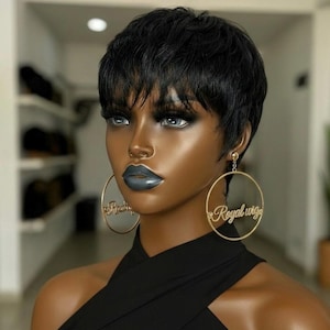 May include: A mannequin head with a short, black wig and large gold hoop earrings. The earrings have the words "Royal Wigs" in a cursive font. The mannequin is wearing a black halter top and has dark makeup.