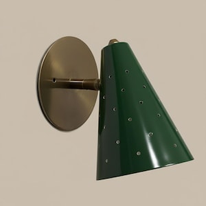 Puede incluir: Aplique de pared verde en forma de cono con placa de montaje y brazo color lat&oacute;n. La l&aacute;mpara tiene una serie de peque&ntilde;os agujeros en el cono. Luminaria para iluminaci&oacute;n interior.