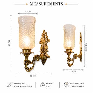 Pu&ograve; includere: Un'applique da parete color oro con base in metallo decorata e paralume cilindrico in vetro con motivo testurizzato. La lampada misura 10 cm di larghezza, 26 cm di profondit&agrave; e 35 cm di altezza, con un peso di 2 kg. Include un'applique.