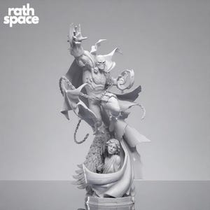 May include: A light gray resin figurine featuring a muscular caped figure in a dynamic pose with outstretched arms and chains, positioned above a smaller sculpted human figure with wings. The text rath space is visible in the top left corner.