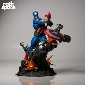 Puede incluir: Estatua detallada de Capitán América en una pose dinámica, luchando contra un enemigo robótico. La figura está vestida con un traje azul, blanco y rojo, sosteniendo su icónico escudo. La base presenta detalles en naranja y negro, con el logo "rath space".