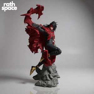 以下が含まれることがあります： ダイナミックなポーズのキャラクターの精巧なフィギュア。赤いマントと黒い衣装が特徴です。フィギュアは銃を持っており、岩の台座に取り付けられています。「rath space」の文字が左上にあります。