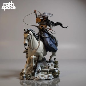 以下が含まれることがあります： 左上に「rath space」の文字が入った、馬に乗った戦士の精巧なフィギュア。戦士は帽子と流れるような衣服を身につけ、鞭を持っています。白い馬は岩場の上で、動きのあるポーズをとっています。