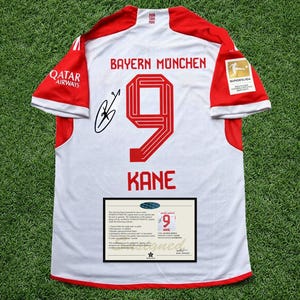 Puede incluir: Camiseta de fútbol blanca y roja del Bayern de Múnich con el número 9 y el nombre KANE en rojo. La camiseta tiene las palabras "BAYERN MUNCHEN" en la parte superior y un logotipo de Qatar Airways. Incluye un certificado de autenticidad.