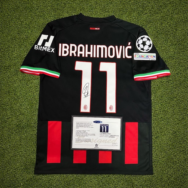May include: Black soccer jersey with the name "IBRAHIMOVIC" and the number "11" in white. The jersey has red and green accents on the sleeves and a BitMEX logo. A signed certificate is displayed below the number.