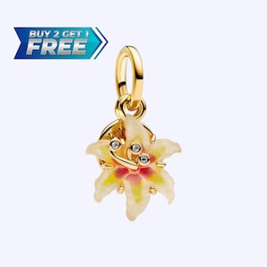 May include: A gold-colored charm with a flower design. The flower has white, yellow, and red petals, with three small, clear gemstones. The charm is suspended from a gold-colored loop. The image also includes the text "BUY 2 GET 1 FREE".