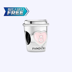 Könnte beinhalten: Ein silberner Charm-Anhänger in Form eines Kaffeebechers mit einem rosa Herz-Design und einer Krone. Der Anhänger trägt den Schriftzug "PANDORA". Das Bild enthält auch den Text "BUY 2 GET 1 FREE".