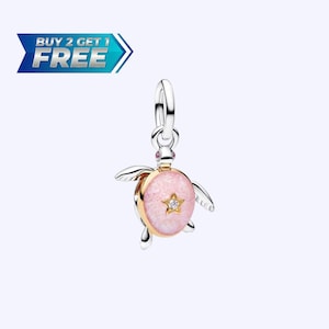 May include: A silver and gold-toned charm in the shape of a turtle. The turtle's shell is pink with a star-shaped gem. The charm has small wings and legs. The text "BUY 2 GET 1 FREE" is in a blue banner.