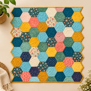 Può includere: Un arazzo trapuntato con un design a patchwork esagonale. La trapunta è composta da vari esagoni di tessuto nelle tonalità giallo senape, verde ottanio, azzurro, corallo e crema, con alcune toppe che mostrano motivi floreali e altre con trapuntatura a spirale.