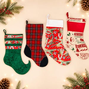 Pode incluir: Quatro meias de Natal dispostas em fila. A primeira é verde com uma ponta enrolada e listras de bengalas doces. A segunda apresenta um padrão xadrez vermelho e preto com calcanhar e ponta pretos. A terceira é vermelha com bengalas doces e um punho branco. A quarta é creme com texto vermelho lendo Winter Wonderland, Believe e Santa Claus.