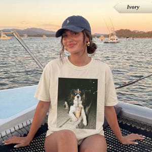 Woman in cream t-shirt with dog wearing sunglasses and holding a coffee drink.