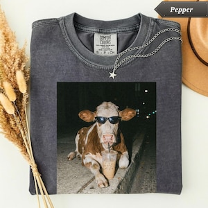 Dark gray t-shirt with a cow wearing sunglasses drinking coffee.