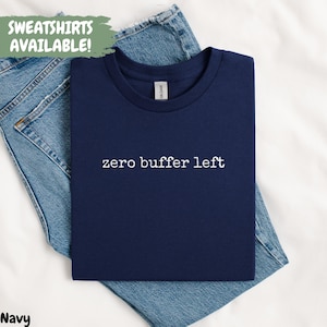 Könnte beinhalten: Marineblaues T-Shirt mit dem weißen Text "zero buffer left". Das T-Shirt ist auf einer blauen Jeans platziert. Die Worte "SWEATSHIRTS AVAILABLE!" stehen in einem grünen Feld oben links.