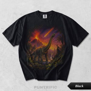 Pode incluir: Uma t-shirt preta com uma estampa gráfica de um dinossauro de pescoço comprido num cenário pré-histórico. A cena inclui uma erupção vulcânica, um rasto de luz no céu, vegetação tropical exuberante e uma pequena cascata ao fundo.