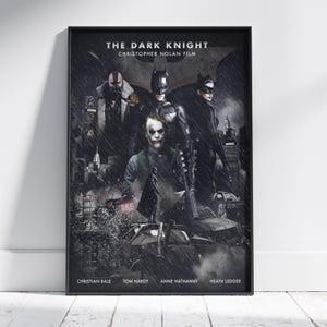 May include: A framed movie poster for The Dark Knight, a Christopher Nolan film. The artwork features Batman, Bane, Catwoman, and the Joker in a dark, rainy city setting with a bat symbol in the background. Cast names are printed at the bottom.