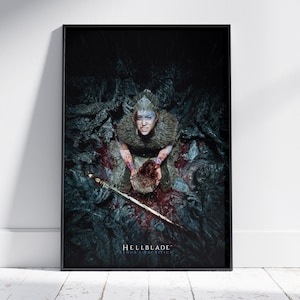 May include: A framed poster featuring a woman with face paint, holding a bloody object, and a sword. The poster has the text "Hellblade Senua's Sacrifice" at the bottom. The color palette is dark with shades of gray, brown, and red.