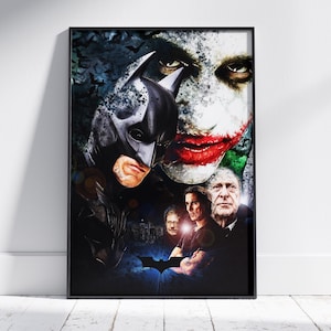 May include: A framed vertical poster featuring a dark, artistic collage of characters from a film. The composition includes a masked hero in a black suit, a face with white makeup and red lips, and three men in the lower section. A bat symbol is visible.