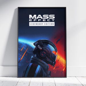 May include: A framed poster featuring the "Mass Effect: Legendary Edition" logo. The artwork depicts a futuristic helmeted figure against a backdrop of space and fiery elements. The color palette includes blues, reds, and blacks.