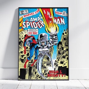 May include: Framed vintage comic book cover art featuring Spider-Man and Stilt-Man. The artwork has a blue, yellow, and red colour scheme, with text that reads "The Amazing Spider-Man" and "High & Mighty!"