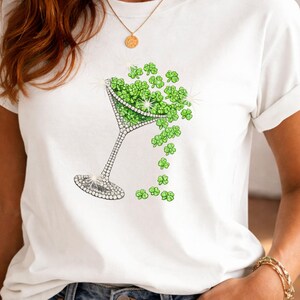 Woman wearing a white T-shirt with a rhinestone-style martini glass design decorated with shamrock clovers.