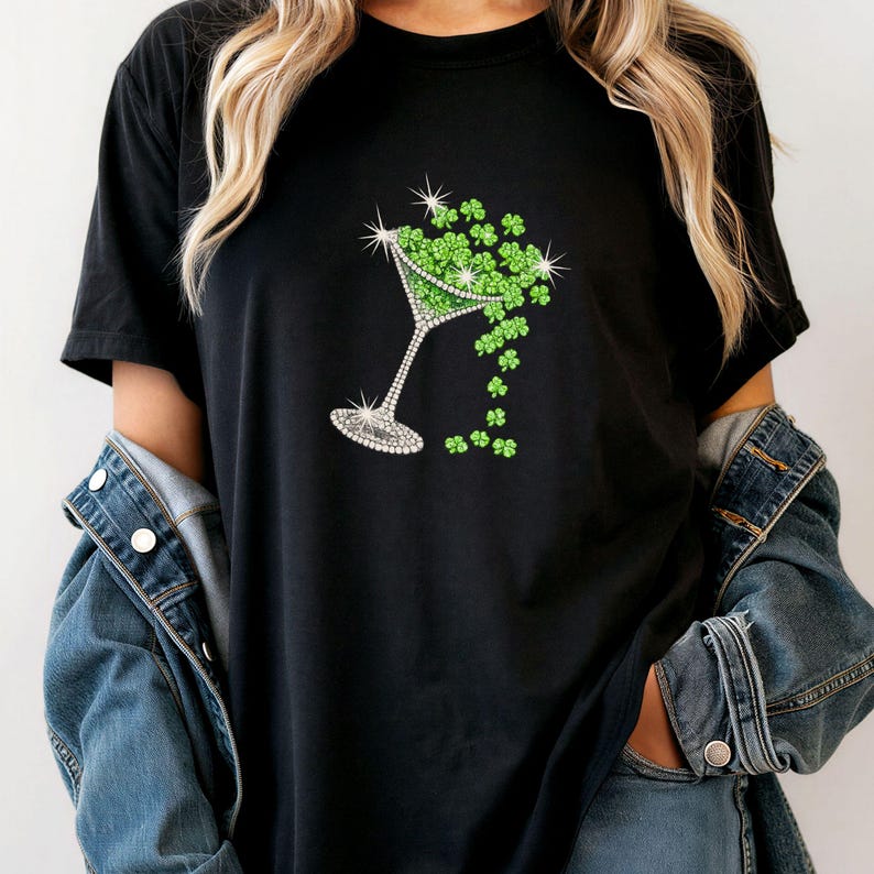 Black t-shirt featuring a sparkling martini glass design filled with green shamrocks. The glass is embellished with rhinestones, and shamrocks cascade from the glass. A festive design for St. Patrick's Day.