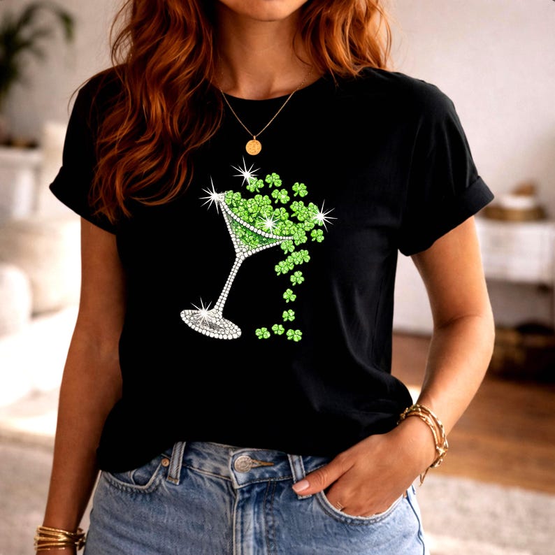 Black t-shirt featuring a martini glass design filled with green shamrocks. The martini glass is embellished with sparkling rhinestones. A festive St. Patrick's Day themed graphic.