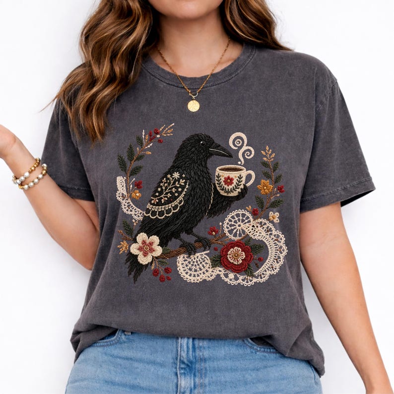 Black crow holding a coffee cup with floral and lace details on a papper Comfort Colors t-shirt