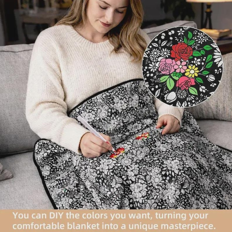 K&ouml;nnte beinhalten: Eine schwarz-wei&szlig; gemusterte Decke mit einer dichten Anordnung von linierten Blumen und Bl&auml;ttern. Ein wei&szlig;er Stift wird verwendet, um bestimmte Bl&uuml;tenbl&auml;tter auf der Stoffoberfl&auml;che mit leuchtenden roten, rosa und gelben Farben auszumalen.