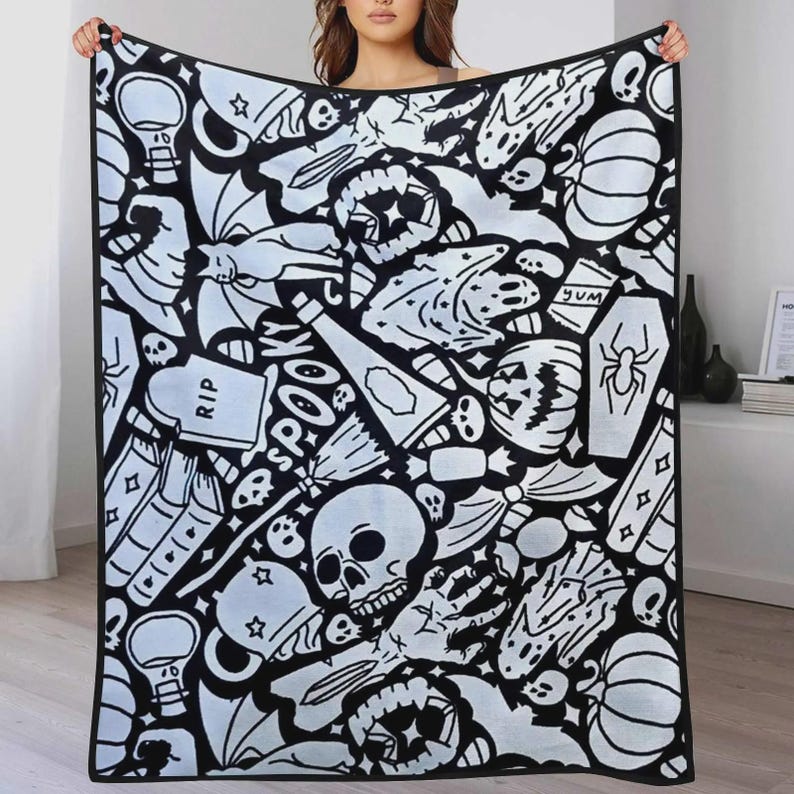 K&ouml;nnte beinhalten: Eine rechteckige Wohndecke mit einem schwarz-wei&szlig;en Muster aus Halloween-Motiven, darunter Totenk&ouml;pfe, K&uuml;rbisse, ein Grabstein mit der Aufschrift RIP, ein Sarg mit einer Spinne, eine Katze, ein Besen und das Wort SPOOKY in gro&szlig;en Buchstaben.