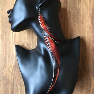 Peut inclure: Une paire de longues boucles d'oreilles pendantes avec des plumes brunes et blanches. Les plumes sont attachées à un crochet argenté.