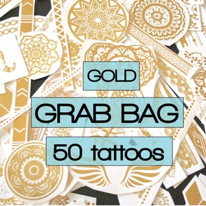 Puede incluir: Un montón de 50 tatuajes temporales dorados en varios diseños, incluyendo formas geométricas, mandalas y flechas. El texto "GOLD GRAB BAG 50 tattoos" está impreso sobre un fondo azul.