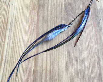 May include: A long, blue and green feather earring with a silver chain and hook. The feathers are layered and have a subtle checkered pattern.