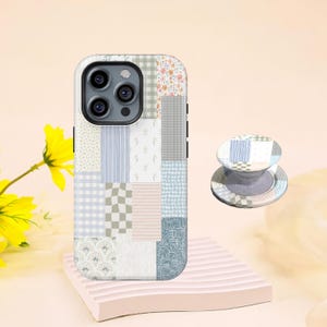 Puede incluir: Una funda de teléfono y un PopSocket a juego con un diseño de patchwork en colores pastel. La funda presenta cuadrados de patrones florales, de cuadros y de rayas en tonos de azul, verde y rosa. El PopSocket refleja el diseño de la funda.