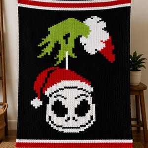 May include: Black knitted throw blanket featuring a pixelated design of Jack Skellington wearing a Santa hat. The blanket has a green and white design above the character and red and white stripes at the top and bottom. A cozy, festive home decor item.