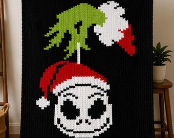 May include: Black knitted throw blanket featuring a pixelated design of Jack Skellington wearing a Santa hat. The blanket has a green and white design above the character and red and white stripes at the top and bottom. A cozy, festive home decor item.