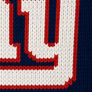 May include: Close-up of a knitted fabric with the letter "Y" in white, outlined in red, against a navy blue background. The knitwear has a textured appearance, suggesting a warm garment.
