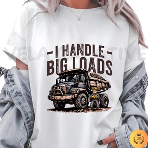 May include: White t-shirt with a graphic of a black dump truck filled with rocks and a construction worker. The text "- I HANDLE - BIG LOADS" is printed above the truck in brown letters.