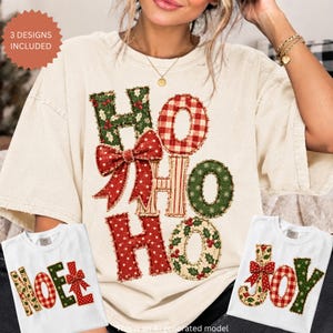 Può includere: Una t-shirt color crema con una grande grafica che riporta il testo HO HO HO in stile patchwork con motivi rossi, verdi e bianchi, tra cui foglie di agrifoglio, bacche, quadri e pois, accentuata da un vistoso fiocco rosso a pois.