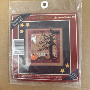 Könnte beinhalten: Ein Mill Hill Autumn Series III Buttoned & Beaded Kit mit dem Titel Eek Bats MHCB71. Die Packung enthält perforiertes Papier, Glasperlen, Keramikknöpfe und ein Band, um ein Halloween-Motiv mit einem Baum, einem Geist und einem Kürbis zu gestalten.