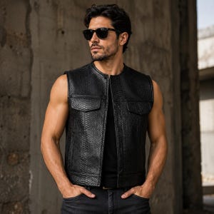 May include: Black sleeveless vest with a snakeskin pattern, featuring two front pockets and a zip-up closure. The vest is worn over a black shirt and paired with dark jeans. The overall style is rugged and fashionable.