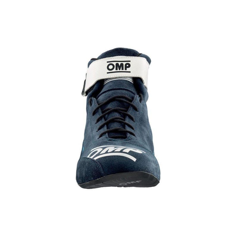 May include: A navy blue suede racing boot with a white strap and the text "OMP". The boot has black laces and a white logo on the side. The sole is black.