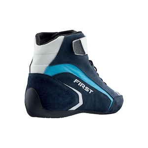 May include: A navy blue and white high-top racing boot with a light blue accent. The word "FIRST" is printed in white on the side of the boot. The boot has a black sole and a velcro strap.