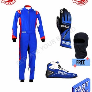 Può includere: Una tuta da corsa blu con dettagli rossi e bianchi, guanti da corsa blu e neri, un passamontagna nero e scarpe da corsa blu e bianche. Il logo Sparco è presente.