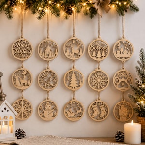 Könnte beinhalten: Ein Set aus fünfzehn runden Holzornamenten in drei vertikalen Reihen, jedes mit filigranen Laserschnitt-Motiven wie Schneemann, Rentier, Schneeflocken, Socken, Kirche sowie den Schriftzügen Merry Christmas, Believe und Let It Snow.